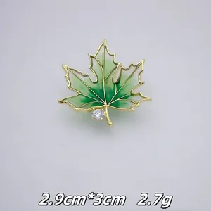 Detailansicht einer eleganten grünen Ahornblatt-Brosche mit Strass-Akzent und Goldrand