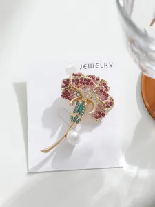 Gros plan d'une broche fleur d'oeillet rose avec cristaux et perle sur carte blanche