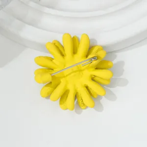 Achteraanzicht van gele madeliefjesbroche met een stevige zilverkleurige speldsluiting detail.