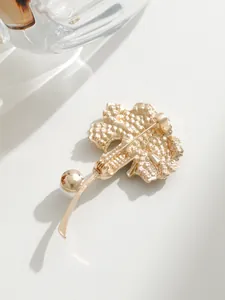 Vue arrière détaillée d'une broche œillet dorée montrant le fermoir de sécurité