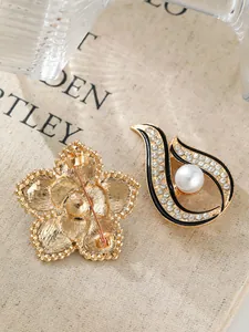 Nahaufnahme einer Brosche mit Perle, Strass, schwarzer Emaille und Goldblume
