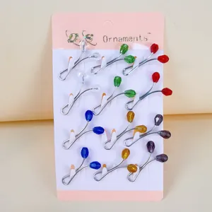 Detailed macro shot of various colorful crystal bead U-shaped scarf clips on a pink card