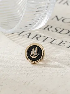 Detailed macro view of a vintage gold-toned sailboat lapel pin with black enamel.