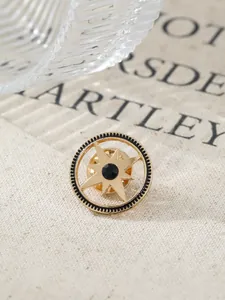 Detailed close-up of a vintage gold starburst brooch featuring a black central gemstone