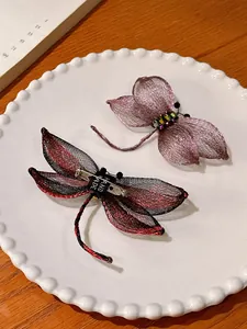 Detailopname van twee elegante handgemaakte libelle speldjes van gevlochten metaaldraad