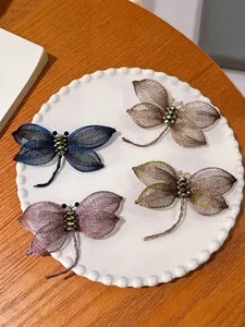 Gedetailleerde weergave van vier kleurrijke handgemaakte libelle broches op bord