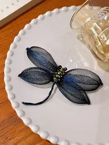 Close-up van elegante libel broche met blauwe draadgaas vleugels op een wit bord