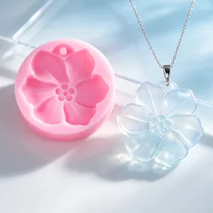 Detailansicht einer Kirschblüten-Silikonform neben einem transparenten Harzblumenanhänger.