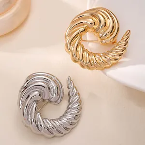 Detailansicht eleganter Spiral-Broschen in Gold und Silber für Damenmode und Anzüge.
