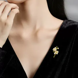 Detailaufnahme einer eleganten Muschelblumenbrosche an einem schwarzen Samtkleid