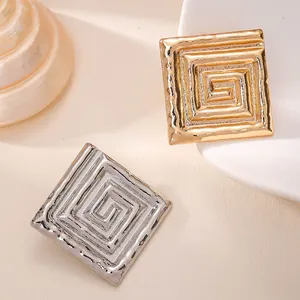 Detailansicht von quadratischen Broschen in Gold und Silber mit geometrischen Mäandermustern
