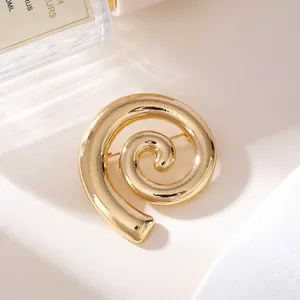 Detailaufnahme einer minimalistischen goldenen Spiralbrosche aus glänzender Legierung