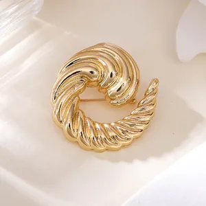 Detailansicht einer eleganten goldenen Spiralbrosche mit strukturierter Oberfläche