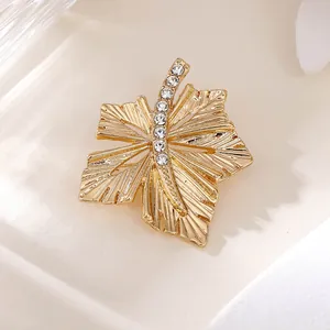 Detailansicht einer goldfarbenen Ahornblatt-Brosche mit feinen Kristall-Strasssteinen