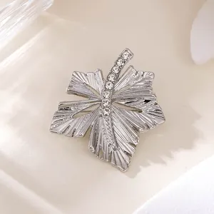 Makrodetail einer silbernen Blattbrosche mit funkelnden Strasssteinen für elegante Anzüge.