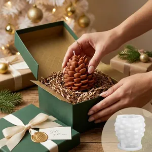 Detailopname van een handgemaakte dennenappelkaars in een geschenkdoos met siliconen mal