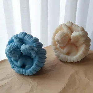 Dettaglio di due candele a conchiglia con angelo artigianali in cera blu e bianco crema