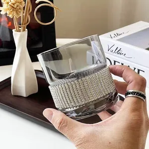 Close-up of a hand holding a luxury smoke grey whiskey glass with a rhinestone wrap detail