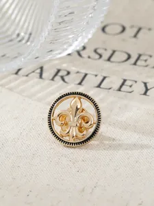 Macro view of a vintage gold fleur-de-lis lapel pin featuring black serrated edges