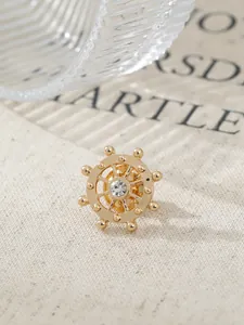 Macro detail of a vintage gold rudder-shaped lapel pin with a sparkling crystal center