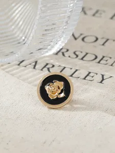 Close-up of a retro gold rose brooch with black enamel and textured rim detail