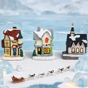 Detailansicht von Miniatur-Weihnachtshäusern aus Harz mit Husky-Schlitten im künstlichen Schnee.