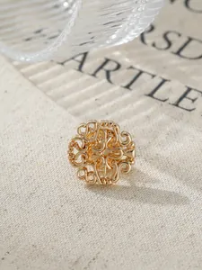 Close-up of vintage golden brooch with intricate root-pattern openwork on textured fabric