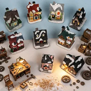 Detailansicht beleuchteter Miniatur-Weihnachtshäuser aus Harz in einer Winterwerkstatt.