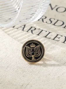 Close-up of vintage gold and black enamel lapel pin with intricate crest design