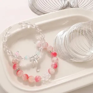 DIY memory wire loops for jewelry making with elegant beaded bracelet examples on a tray