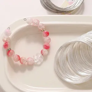 DIY jewelry making kit featuring silver memory wire coils and a pink beaded bracelet