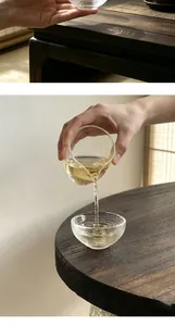 Detail of a Japanese clear glass teacup with handcrafted texture on a wooden table