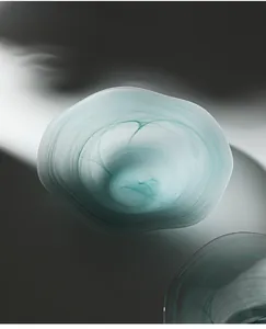 Artistic close-up of a teal frosted glass fruit bowl with irregular cloud-like pattern