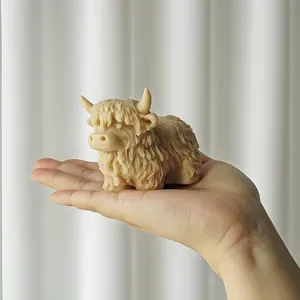 Vue détaillée d'une bougie faite main en forme de vache écossaise dans une main
