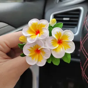 Detalle de un adorno de resina con forma de flor de plumeria hecho a mano para coche