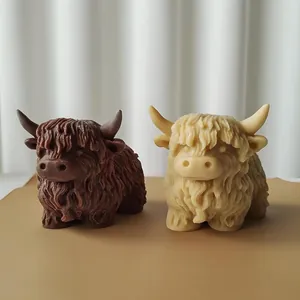 Détail de deux bougies en forme de vache Highland faites à la main, marron et crème.