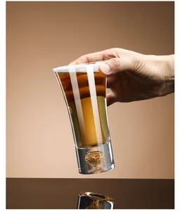 Close-up detail of a high-end crystal beer glass featuring a decorative gold leaf inlay base.