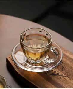 Detailed view of a clear heat-resistant glass teacup and saucer on a rustic wood board