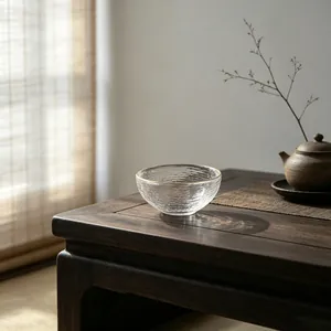 Elegant Japanese style hammered glass teacup with a gold rim on a dark wooden table