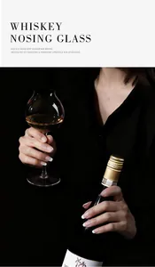 Close-up of an elegant crystal nosing glass held by a person in dark professional attire