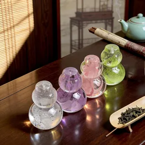 Elegant crystal glass gourd-shaped tea lid rests in four colors on a traditional tea table.