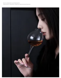 Elegant woman sipping from a crystal tulip-shaped wine glass in a dark minimalist setting