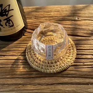 Detailed macro view of Japanese handmade textured glass cup on woven coaster in sunlight