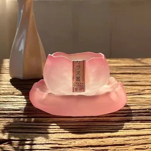 Vue détaillée d'une tasse à thé en verre givré rose faite à la main avec bord fleuri.