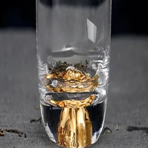 Macro detail of hand-painted gold mountain design at the base of a clear glass tea cup.