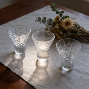 Set of three textured glass tea cups on linen cloth with warm lighting
