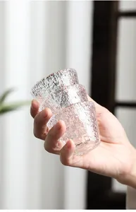 Detailansicht von gestapelten japanischen Glasteetassen mit Hammerschlag-Optik in Hand.