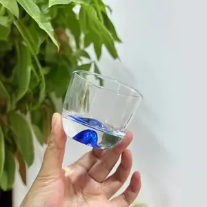 Handheld Japanese style clear glass tea cup with a unique blue mountain base design