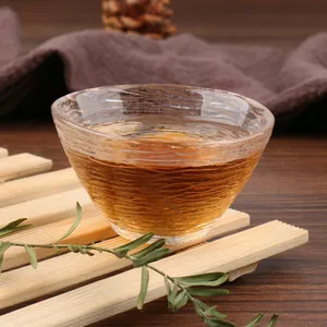 Close-up of a Japanese hammered glass tea cup with textured wave pattern and golden tea