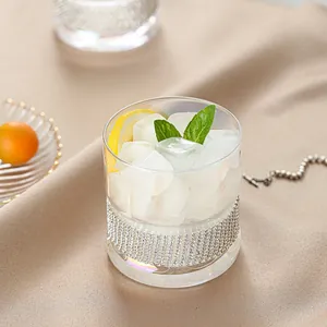 Elegant luxury rhinestone crystal whiskey glass filled with fresh ice cubes and lemon slice.